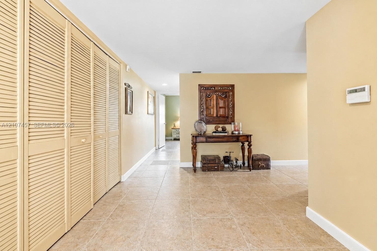 Neutral tile flooring and extensive built-in louvered-door closets