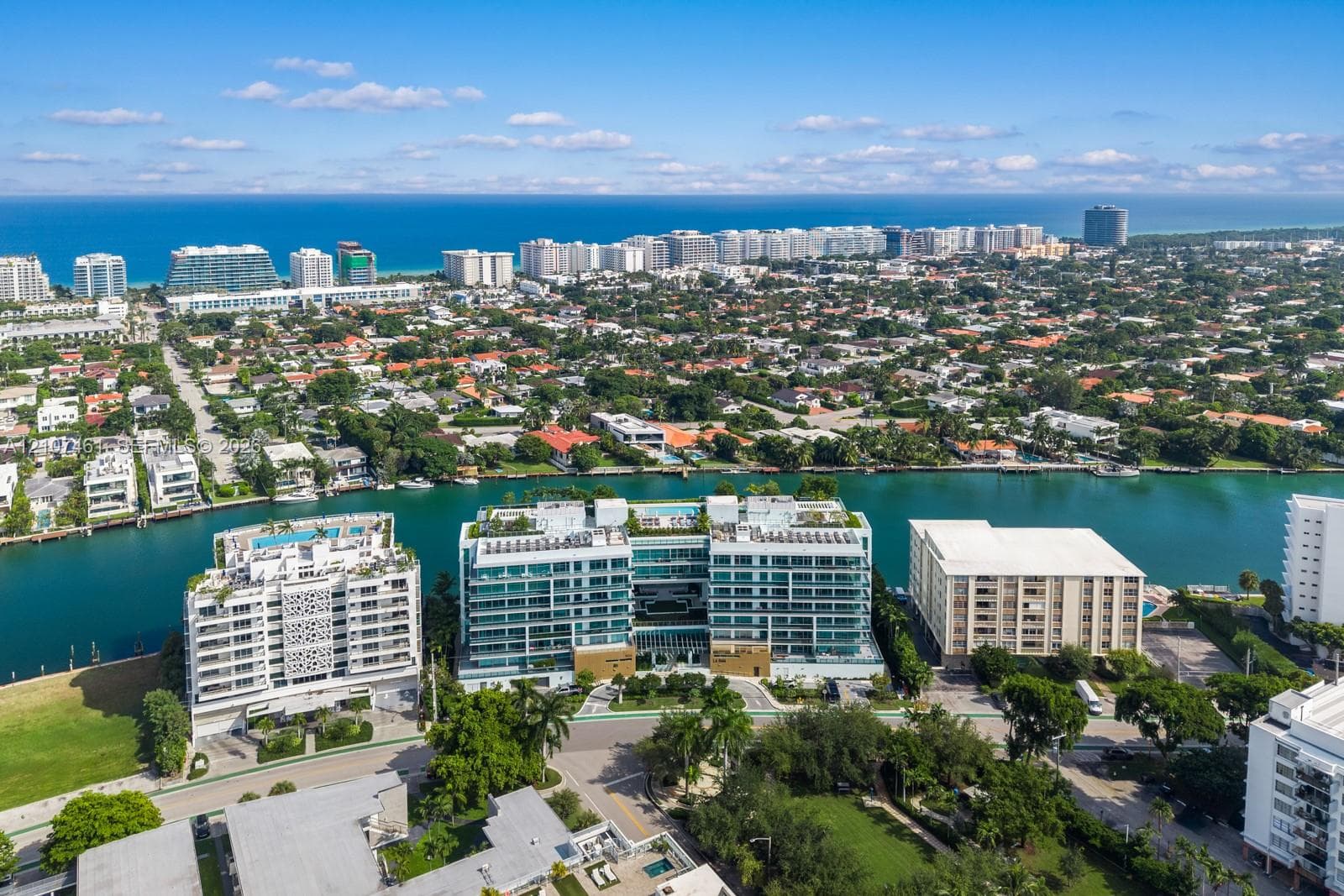 Aerial perspective of a multi-story waterfront residential building featuring floor-to-ceiling glass paneling, private balcony terraces, and rooftop amenities