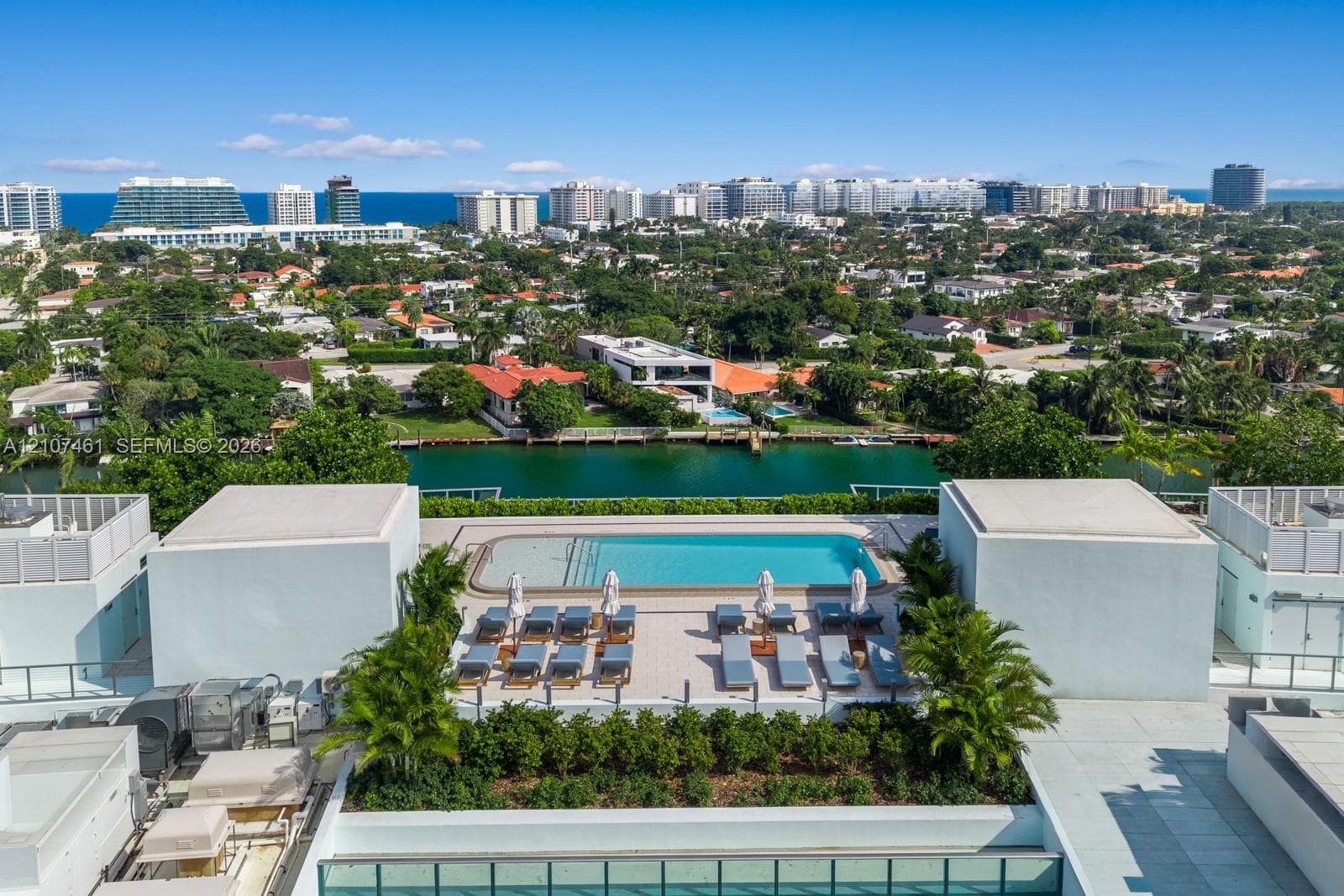 Rooftop swimming pool with paved decking and integrated landscaping, featuring a backdrop of coastal and urban scenery
