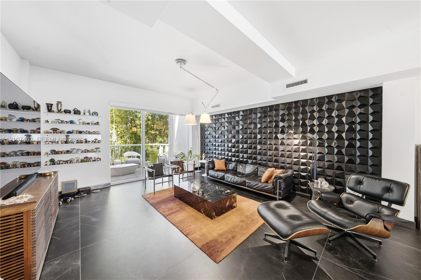 Living area featuring a three-dimensional geometric accent wall, oversized tile flooring, recessed lighting, and sliding glass doors to the exterior
