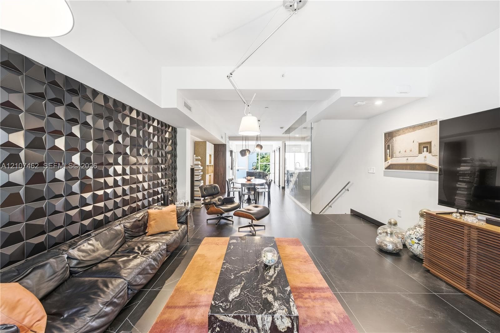 Geometric three-dimensional feature wall, large-format tile flooring, adjustable multi-arm pendant lighting, and recessed ceiling lighting