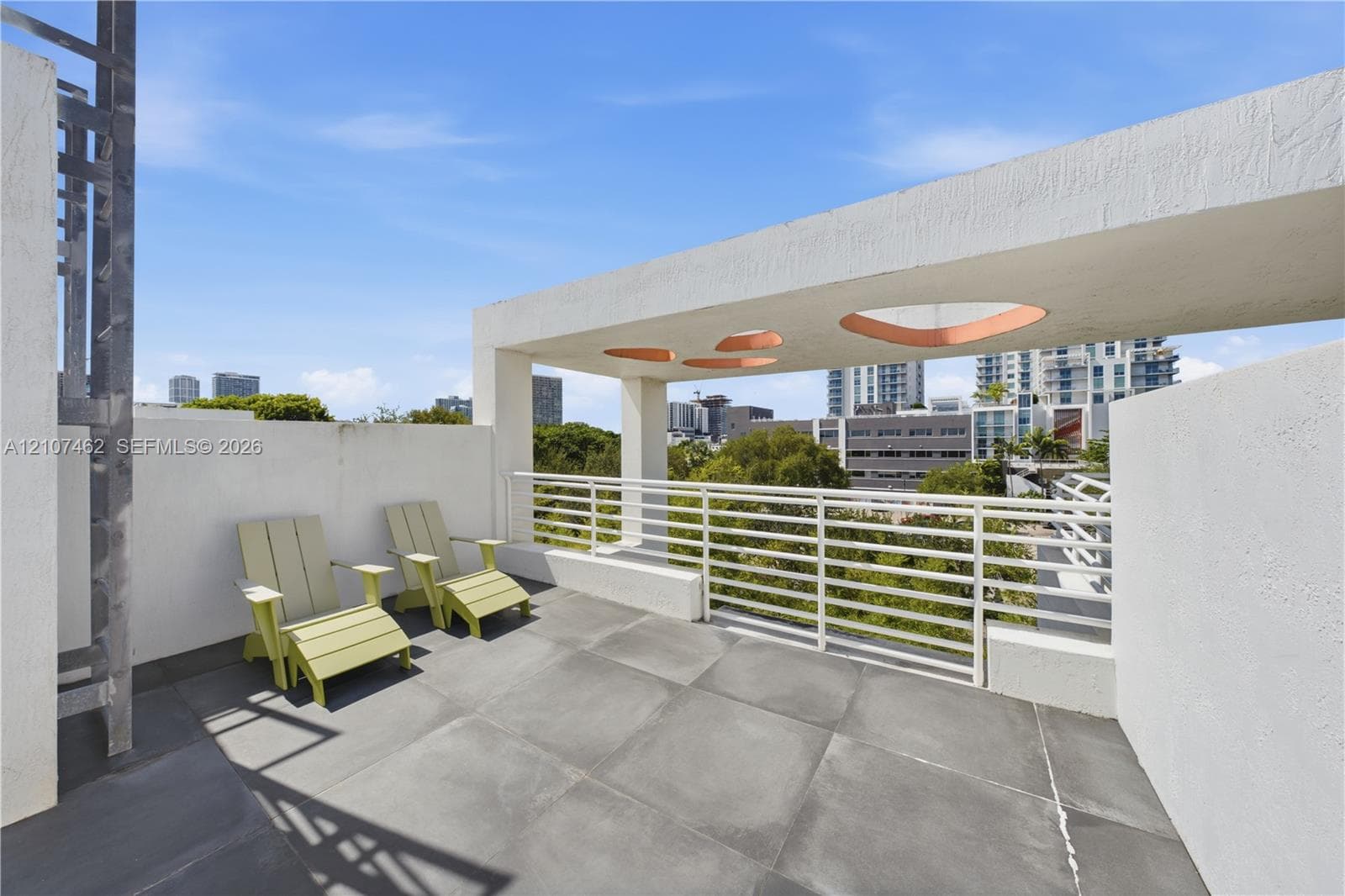 Rooftop terrace featuring large-format tile flooring, a white metal railing, and a geometric concrete overhead structure with circular cutouts