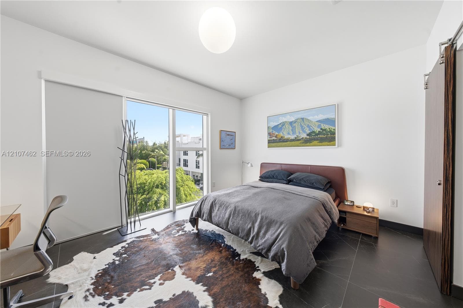 Floor-to-ceiling windows featuring mountain scenery, dark large-format tile flooring, and a sliding wood-finish door