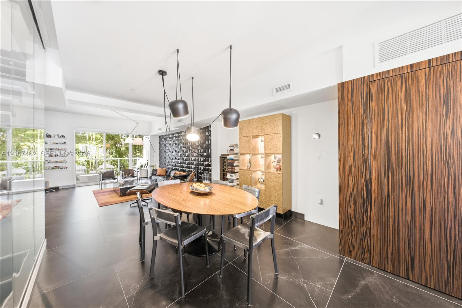 Large-format tile flooring, wood-grain paneling, custom built-in display cabinetry, and contemporary multi-pendant lighting