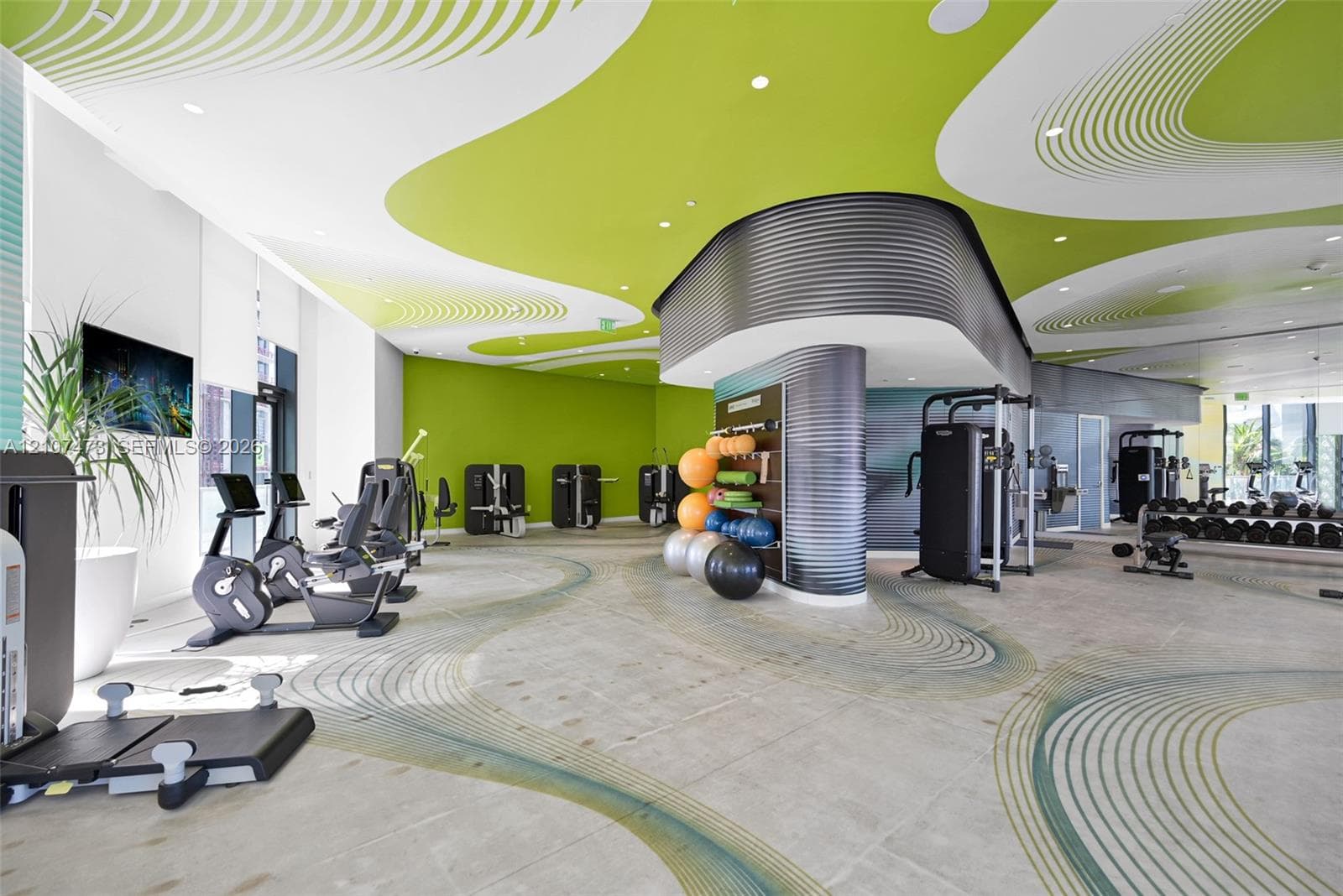 Fitness center featuring expansive floor-to-ceiling windows, high-contrast patterned ceiling, curved corrugated-metal structural accents, and large-format tile flooring
