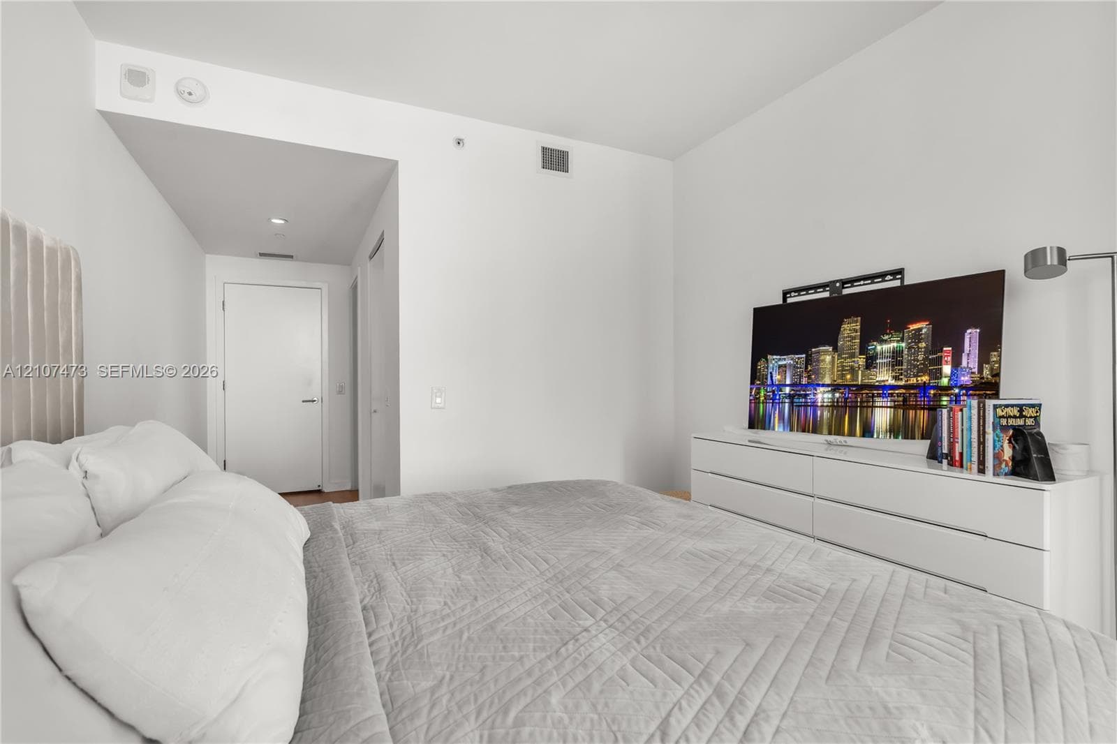 Neutral-toned interior space featuring recessed ceiling lighting, smooth white walls, and a dedicated hallway entry