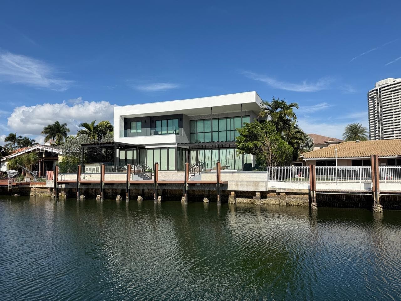 Contemporary waterfront residence featuring multi-level glass facades, a private bulkhead dock, and integrated pergola structures