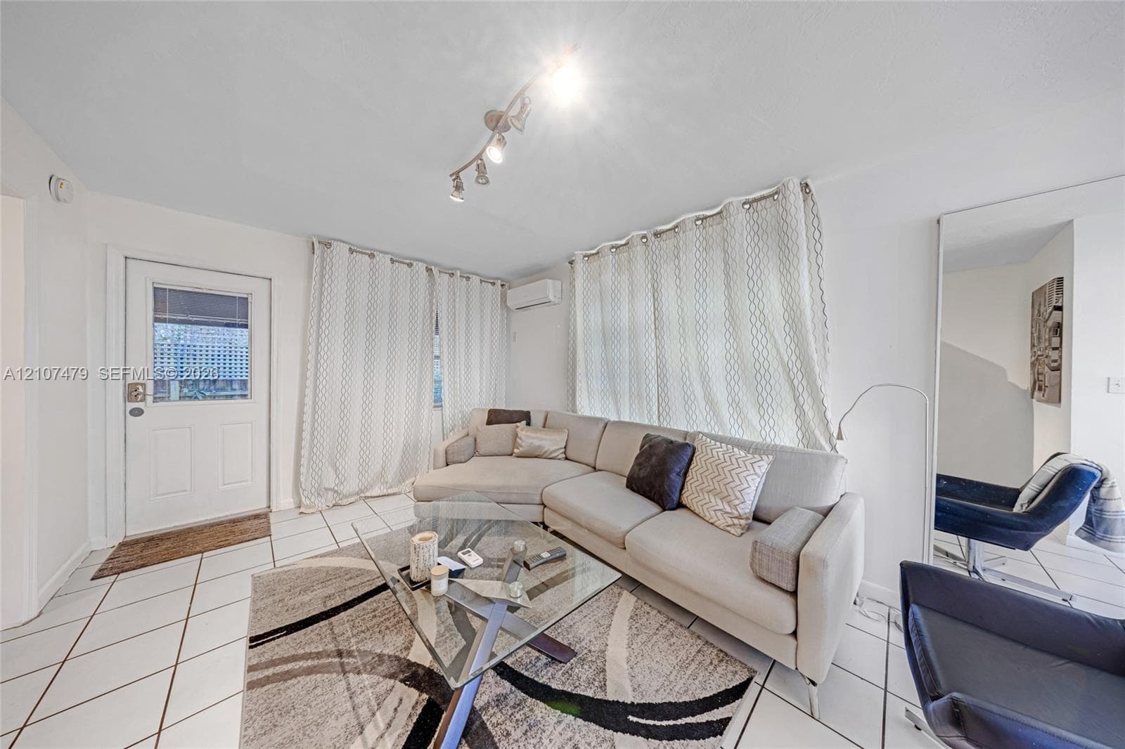 Interior space featuring white tiled flooring, a mounted ductless mini-split HVAC unit, and track lighting