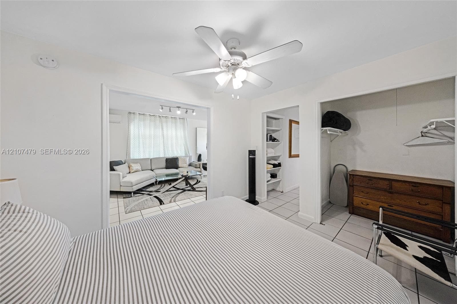 Room featuring tile flooring, ceiling fan with integrated lighting, built-in shelving, and an open closet