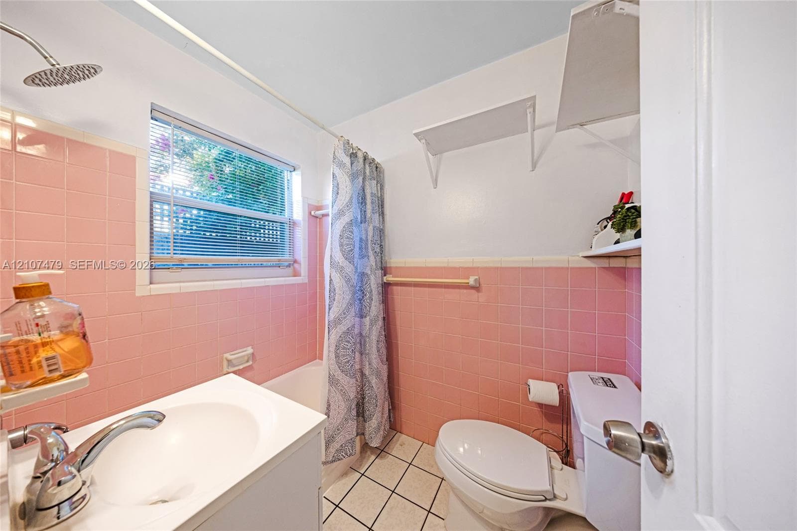Bathroom featuring pink wall tile, a white vanity with an integrated sink, a porcelain toilet, and square floor tiles