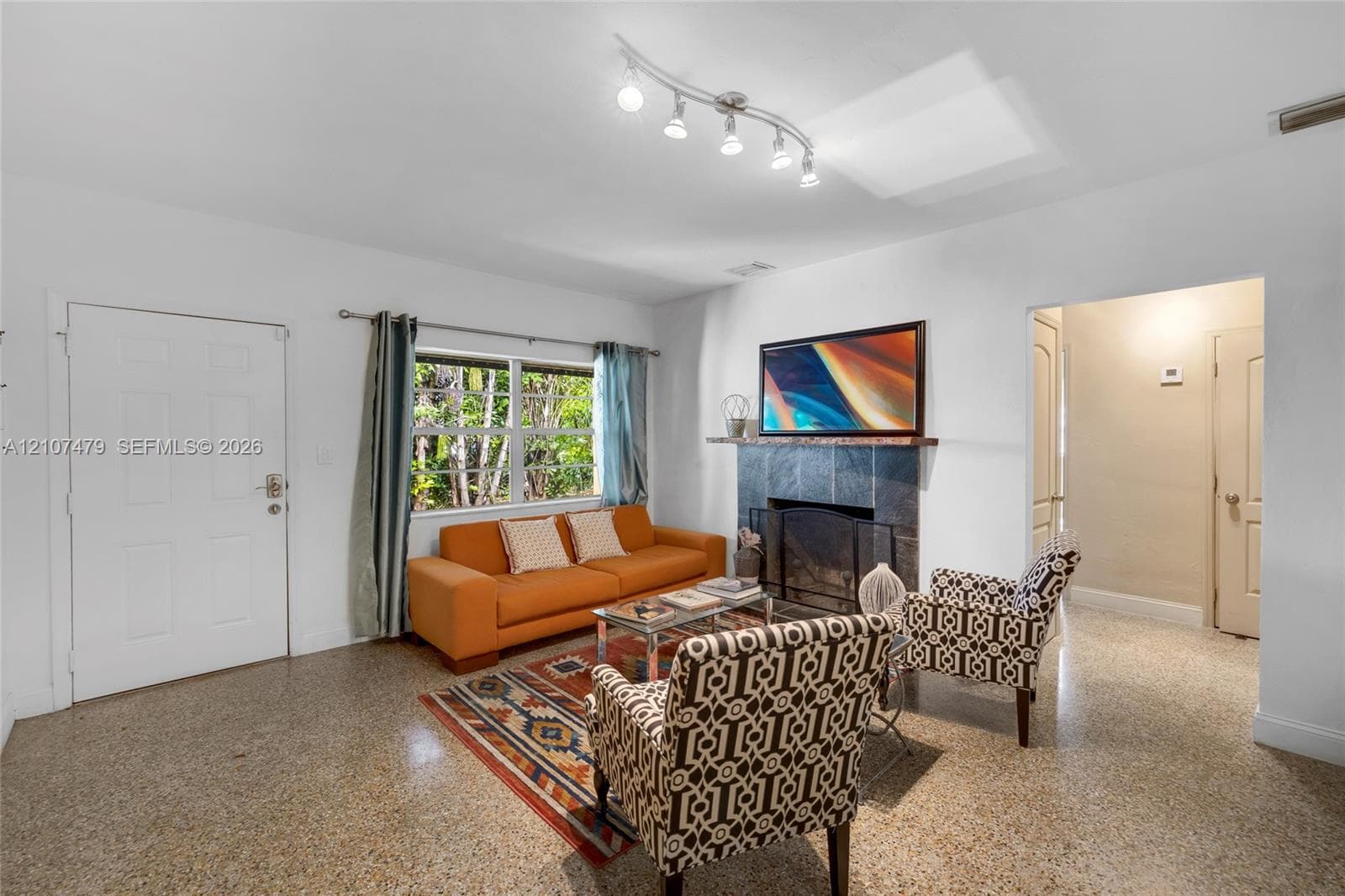 Main living area featuring tile flooring, a wall-mounted ductless air conditioning unit, and directional track lighting