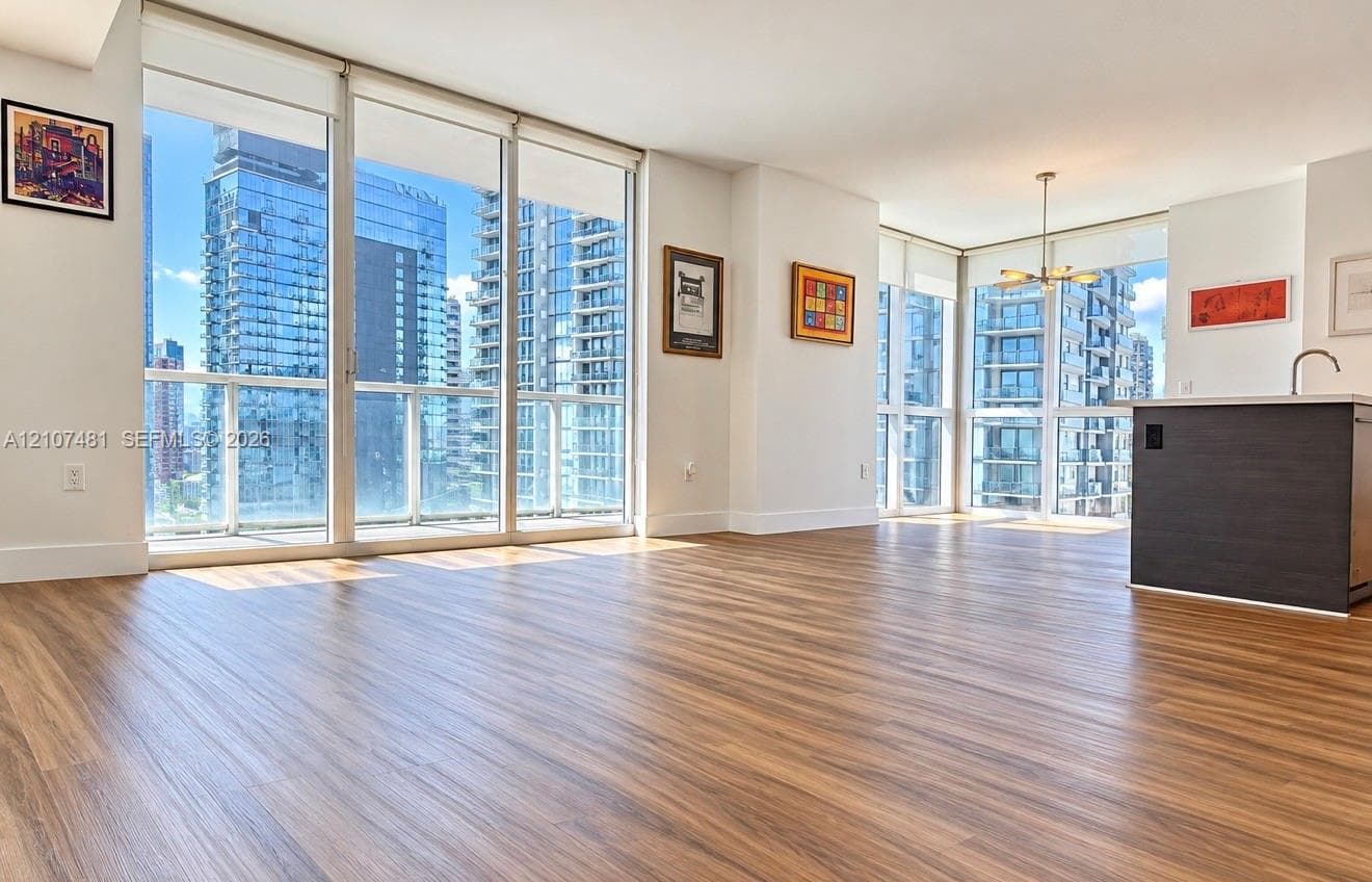 Floor-to-ceiling windows, wood-finish flooring, and kitchen island with a built-in sink