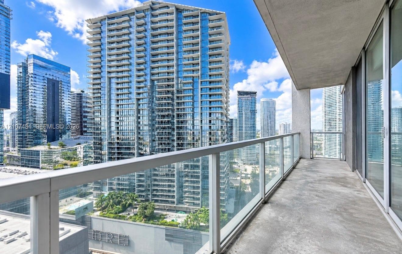 Covered balcony featuring concrete flooring and a glass-paneled railing