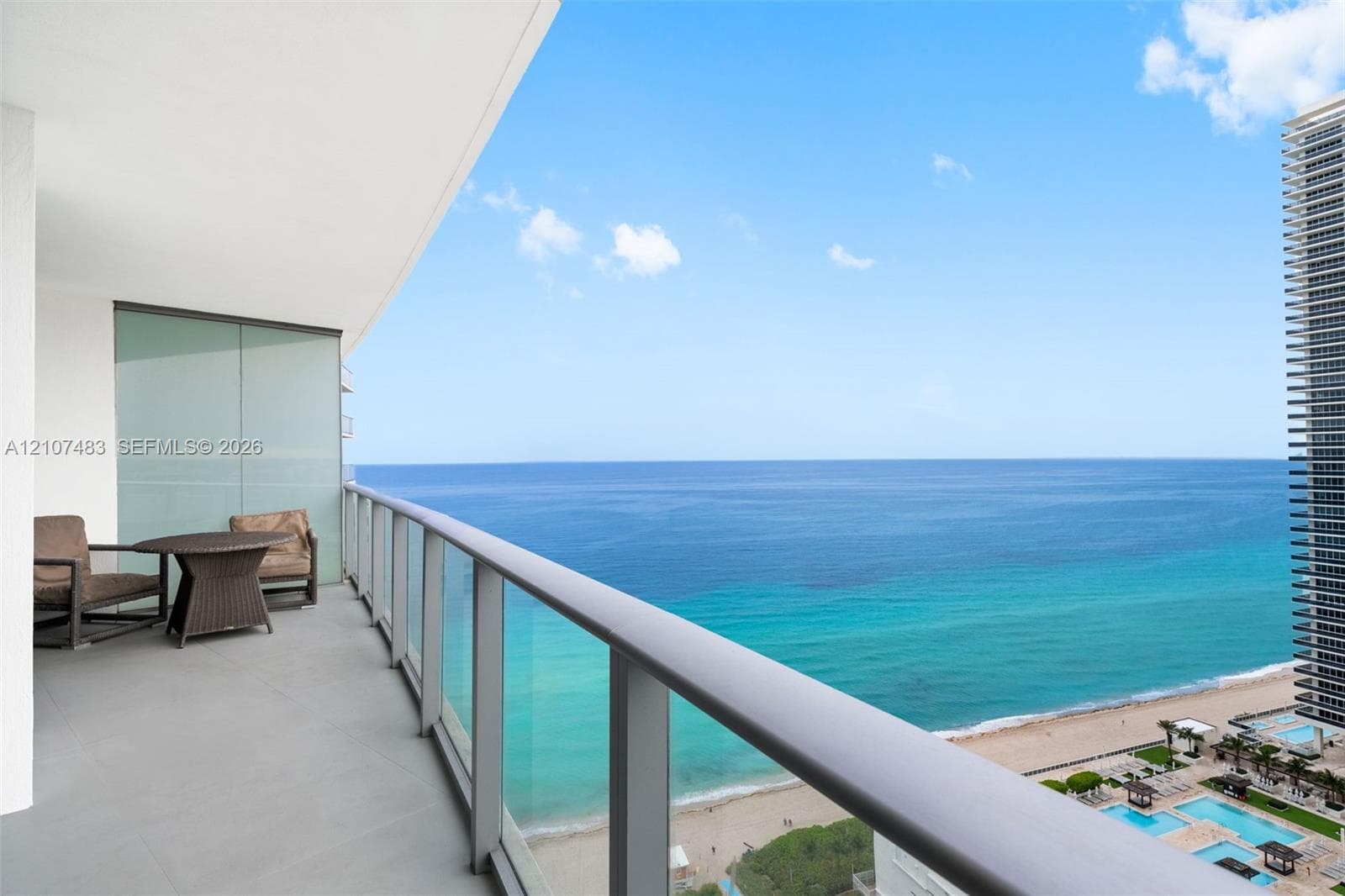 Private balcony featuring neutral-toned tile flooring, minimalist metal railings, and clear glass panels