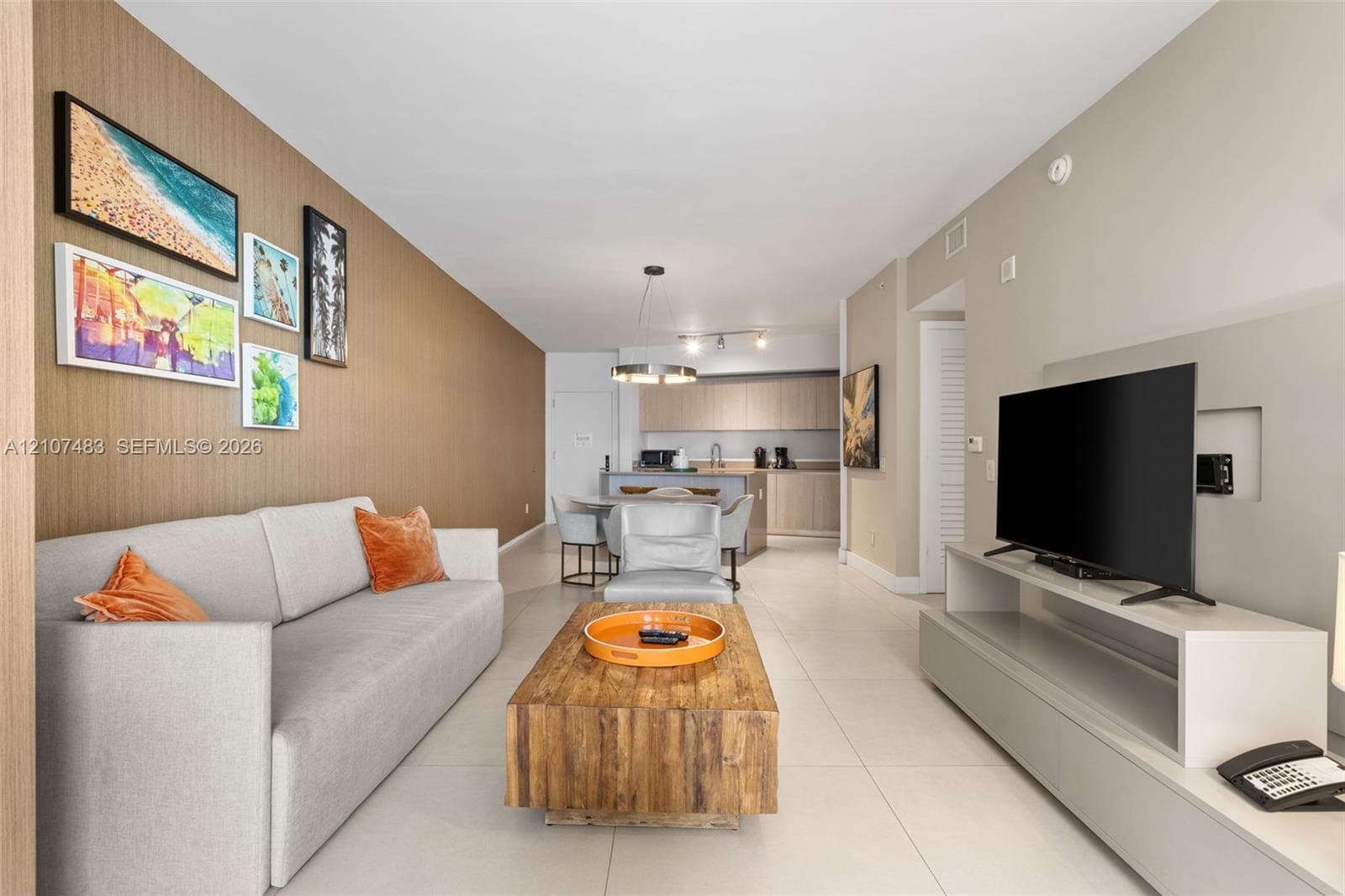 Open concept interior featuring large-format tile flooring, a textured accent wall, and recessed media wall shelving