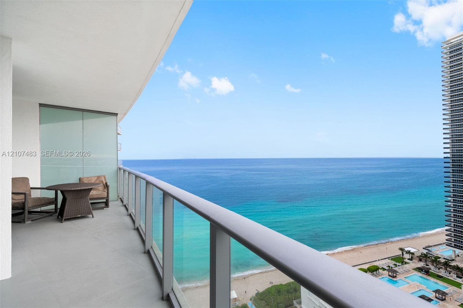 Covered balcony featuring concrete flooring, a glass-panel railing, and an expansive horizon of the ocean