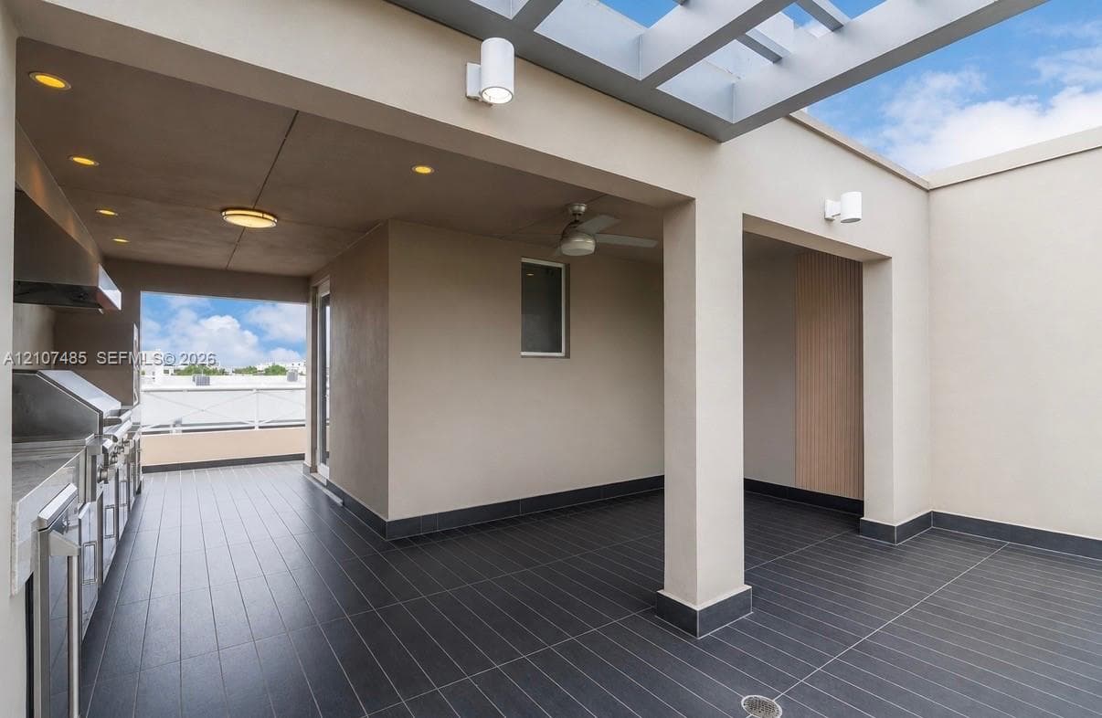 Covered rooftop terrace featuring a pergola, recessed lighting, dark tile flooring, and an outdoor kitchen equipped with a built-in stainless steel grill