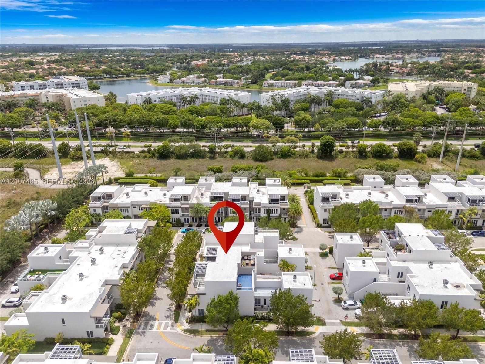 Aerial perspective of a multi-level residential property featuring a rooftop terrace, private pool, modern exterior architecture, and mature landscaping