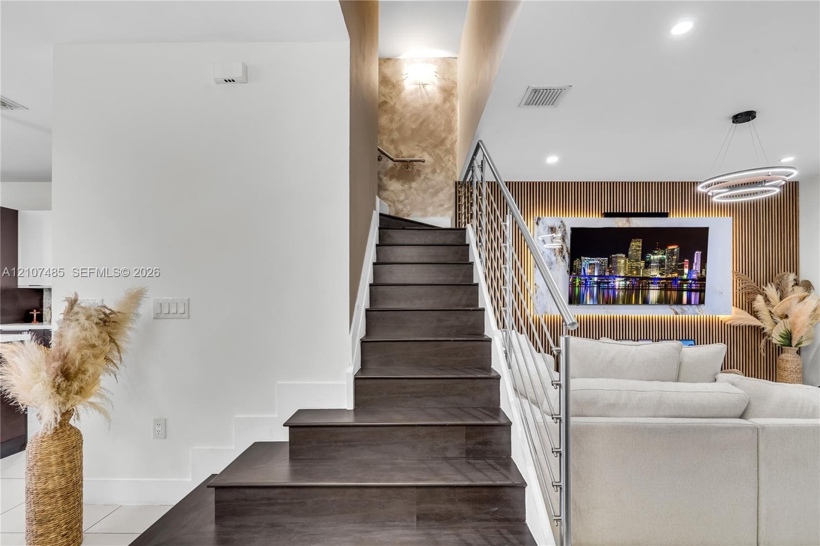 Staircase featuring dark wood-finish treads, a custom cable railing system, vertical slat wall paneling, and recessed lighting