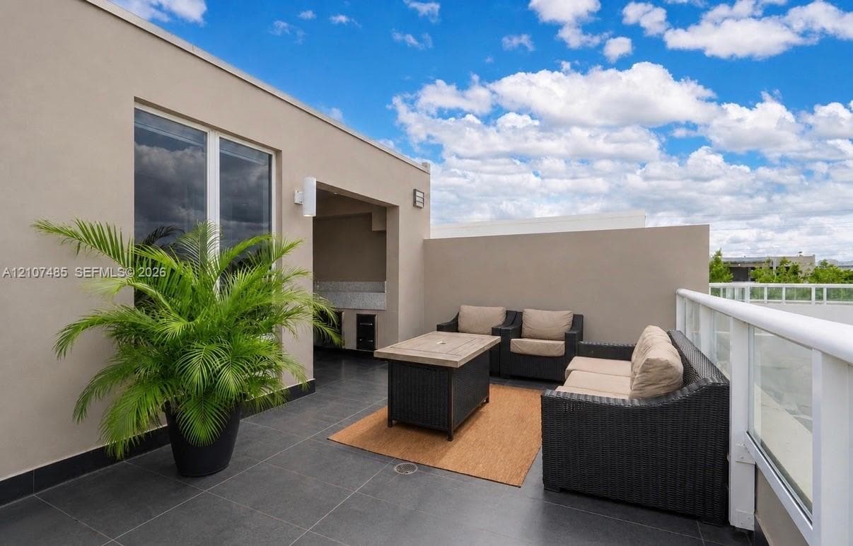 Rooftop terrace featuring charcoal tile flooring, integrated outdoor kitchen cabinetry with stone countertops, and a white glass-panel railing