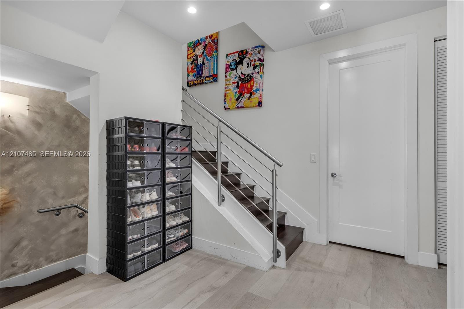 Staircase featuring dark wood treads, white risers, and a stainless steel horizontal cable railing system, complemented by wood-finish flooring and recessed ceiling lighting