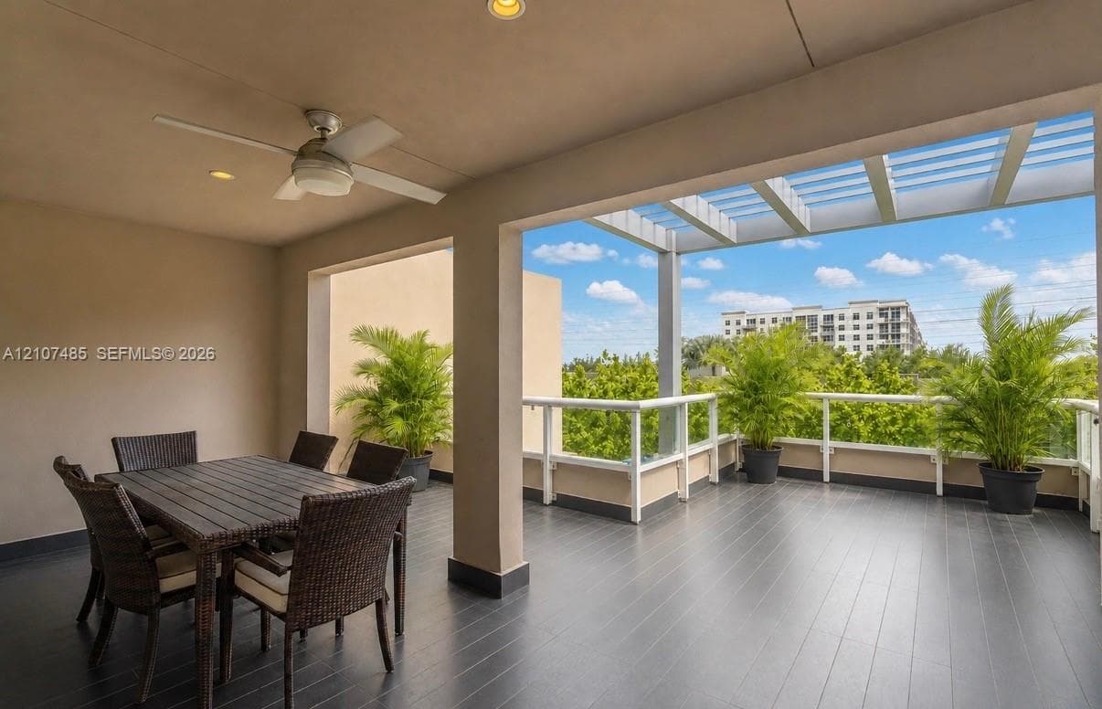 Covered terrace featuring dark plank flooring, a built-in ceiling fan, recessed lighting, and a pergola-style overhead structure with white railing