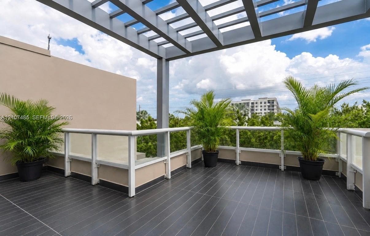 Terrace featuring dark tile flooring, a metal pergola, and glass panel railing