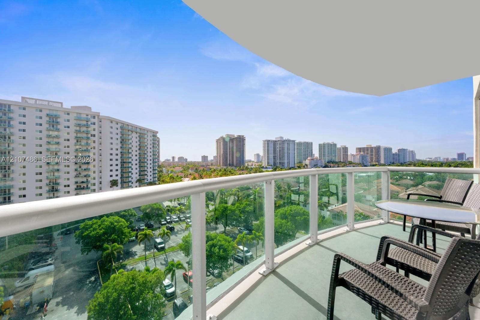 Private balcony featuring glass-panel railings, white metal framing, and a concrete floor