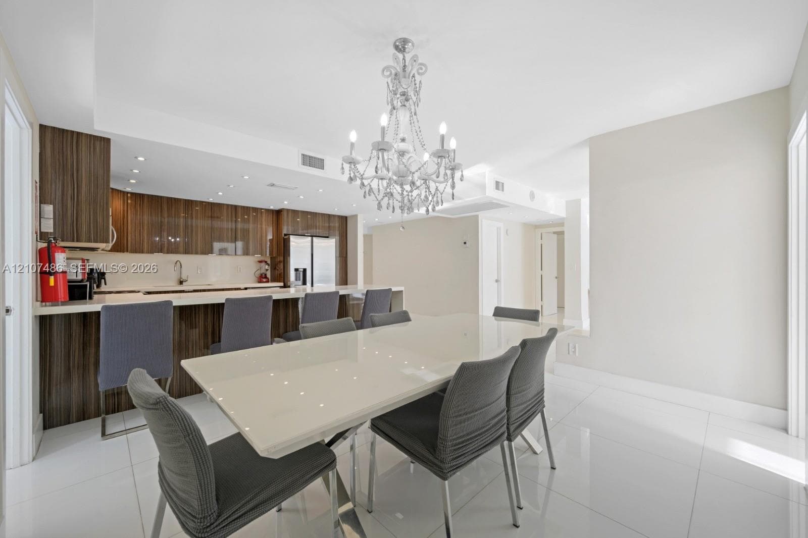Kitchen featuring horizontal-grain wood cabinetry, integrated stainless steel appliances, and a breakfast bar with stone-surfaced countertops