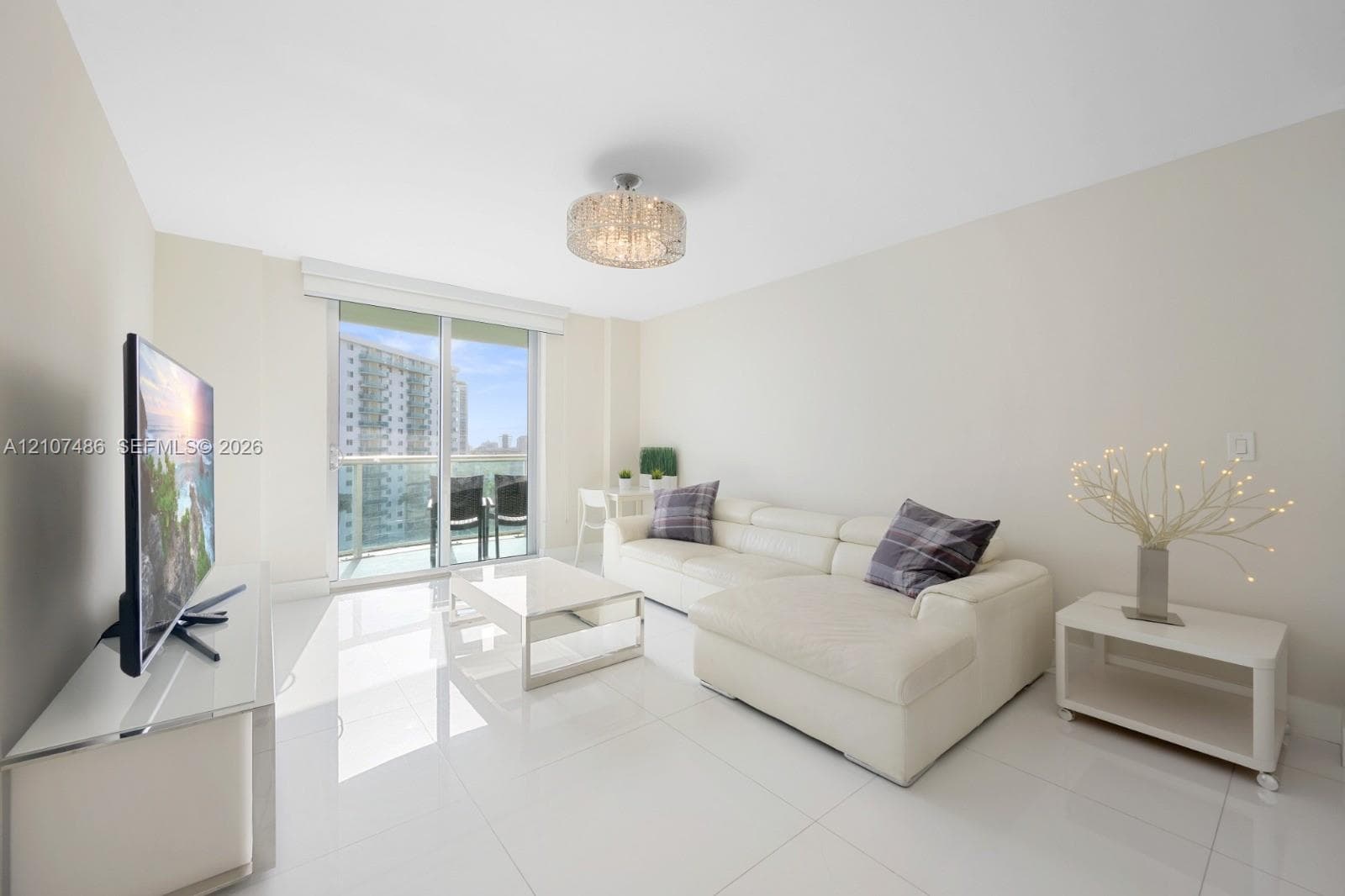 Large-format polished tile flooring, floor-to-ceiling glass sliding doors, private balcony, and decorative drum-style ceiling light fixture