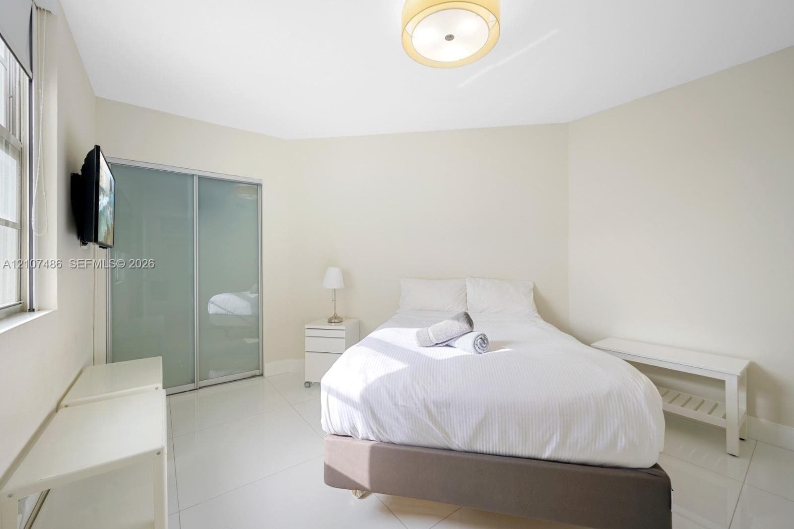 Bright room featuring large-format tile flooring, sliding glass-panel closet doors, and a neutral color palette