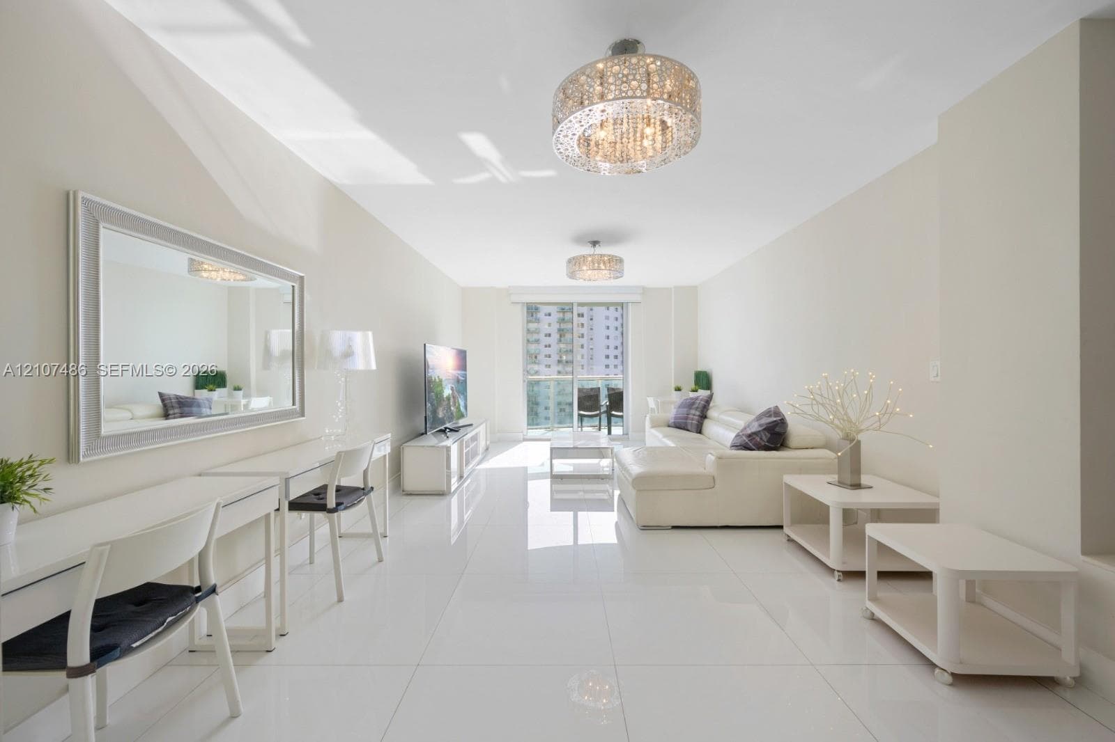 Polished tile flooring, dual decorative semi-flush mount light fixtures, and floor-to-ceiling glass sliding doors opening to an exterior balcony