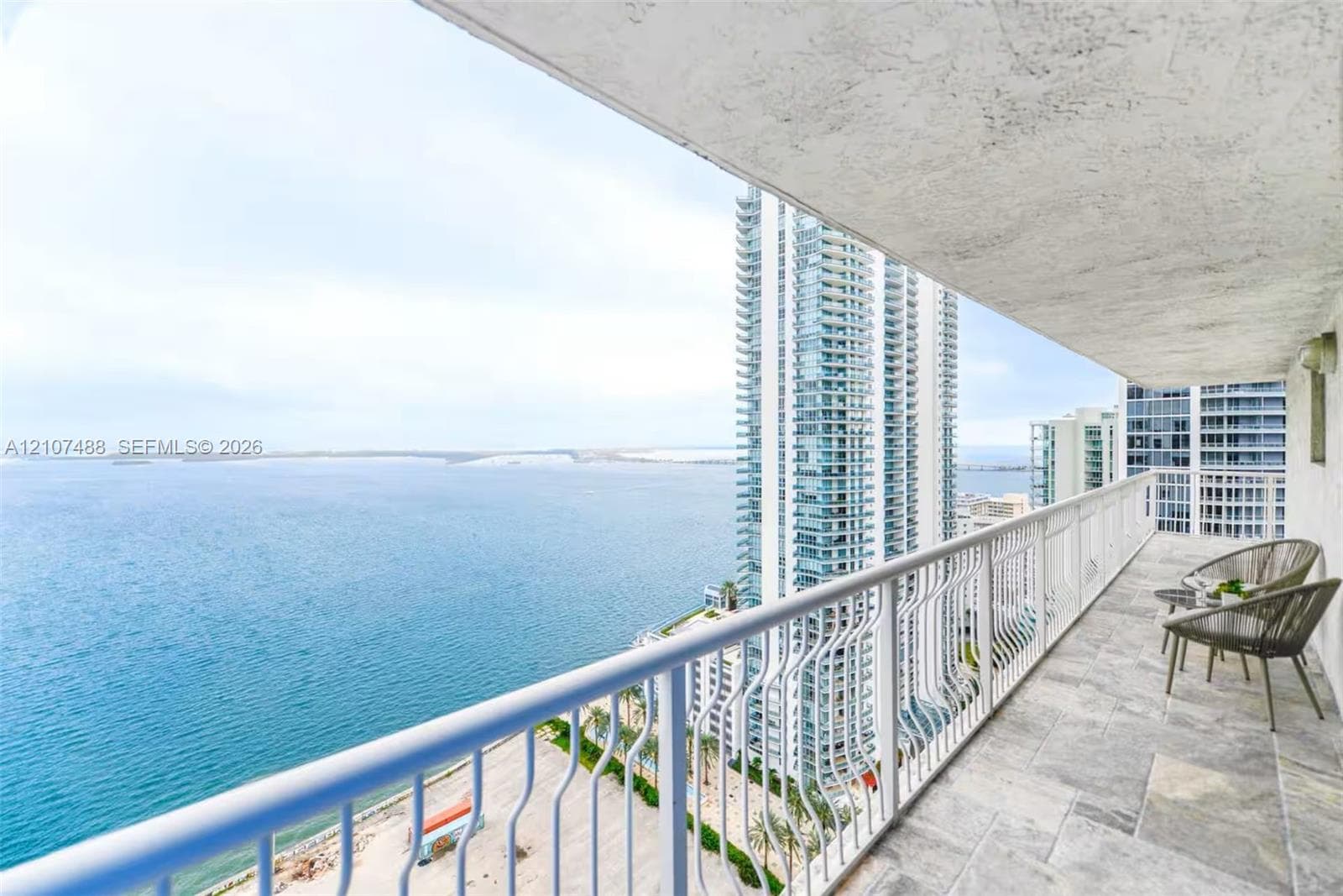 Covered balcony featuring stone-finish tile flooring and a white metal railing