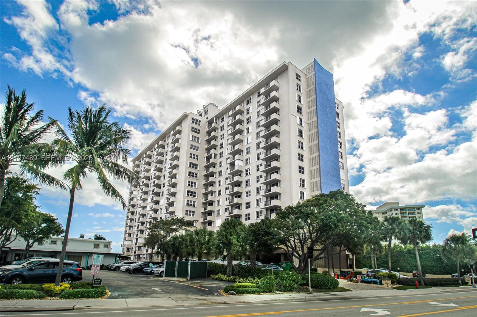 High-rise exterior featuring multi-level private balconies, white structural facade, and accent blue vertical panelling