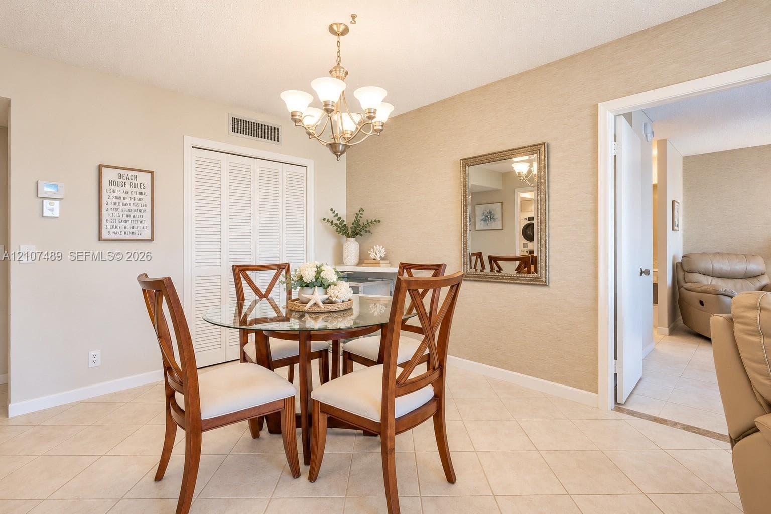 Dining area featuring textured wall finish, ceramic tile flooring, a multi-light metal chandelier, and a louvered-door storage closet