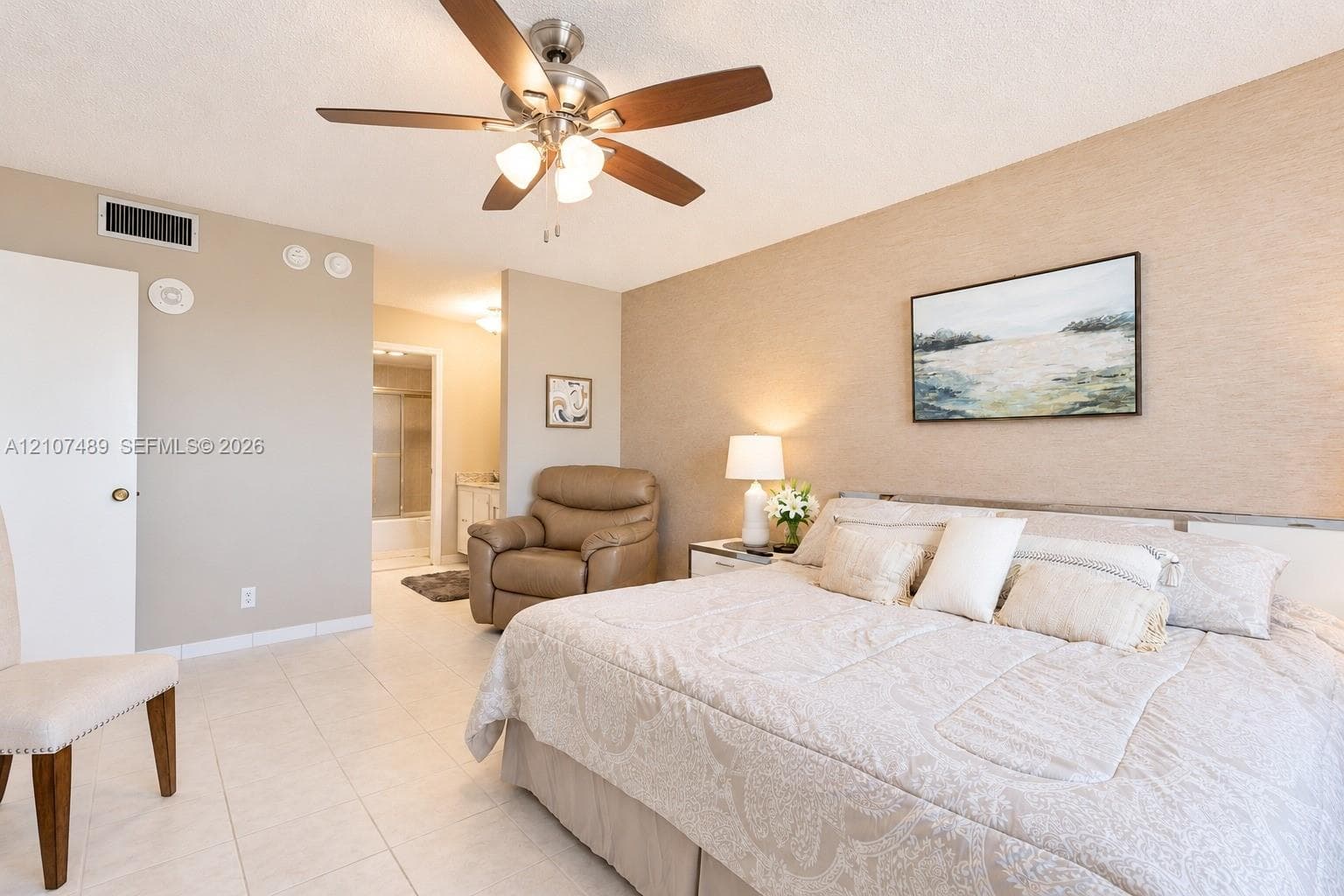 Spacious room featuring neutral tile flooring, a brushed-nickel ceiling fan with integrated lighting, and textured wall finish