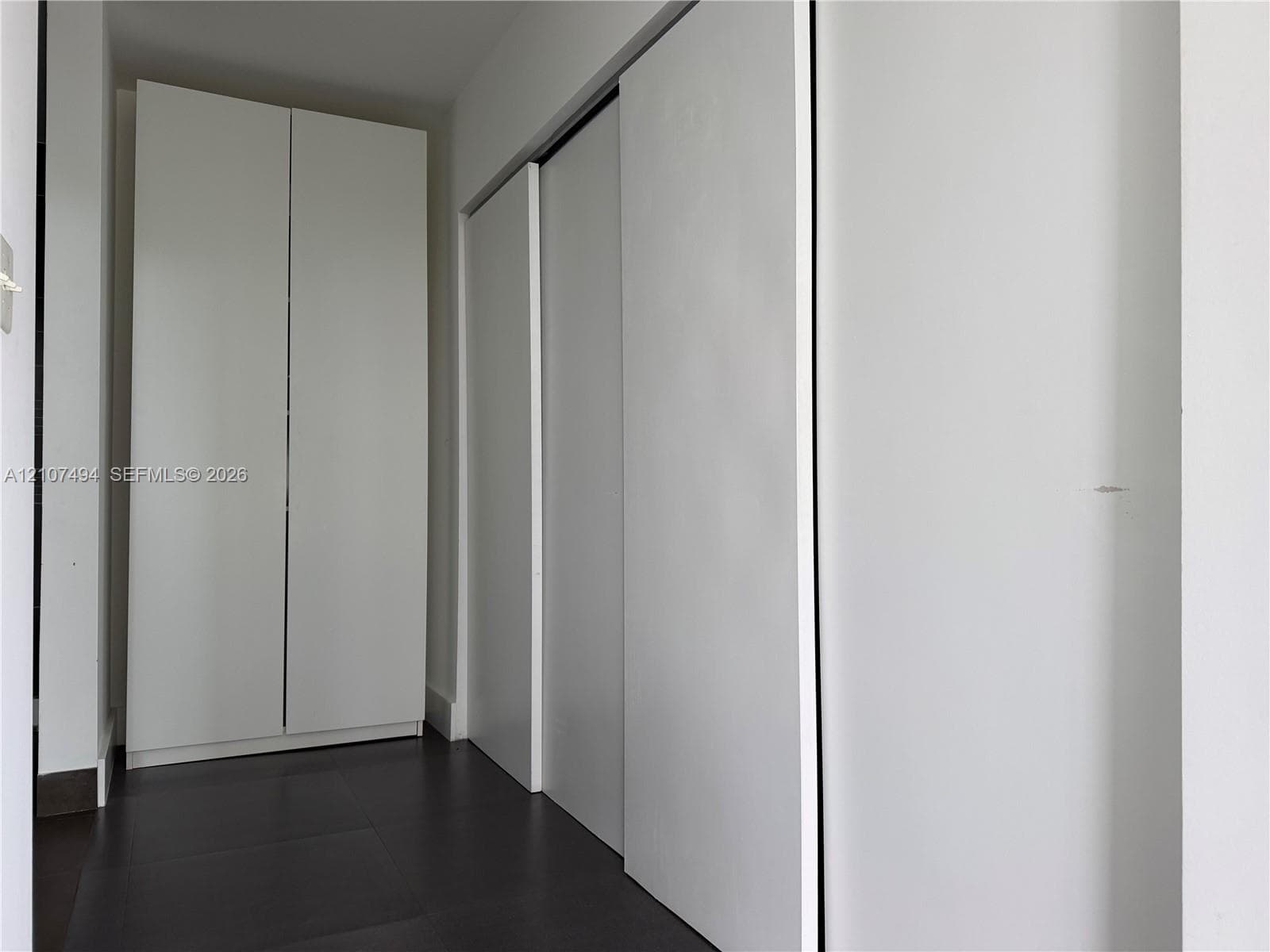 Floor-to-ceiling cabinetry with smooth white finish and dark tile flooring