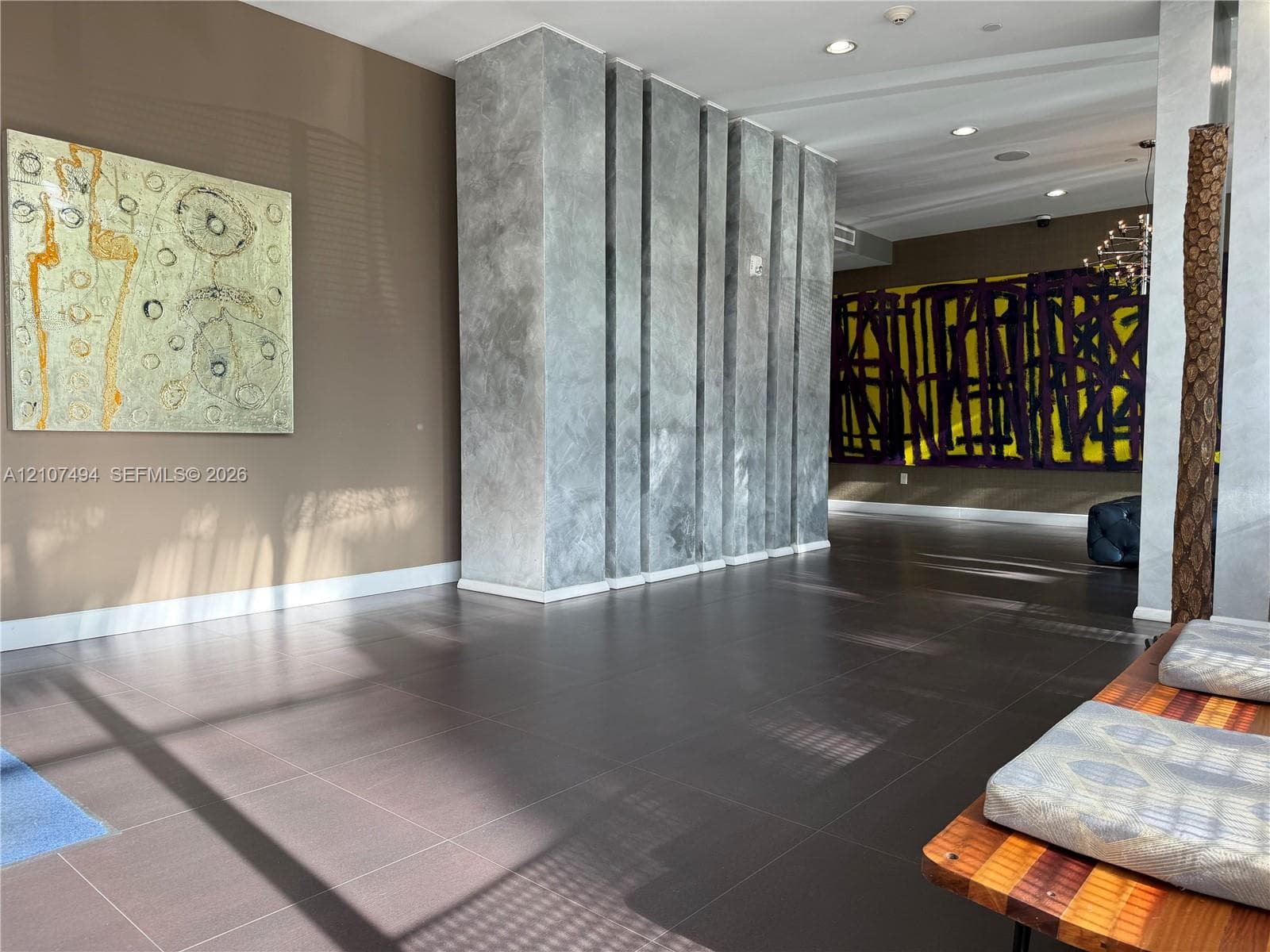 Large-format tile flooring, textured architectural column with vertical detailing, and recessed ceiling lighting