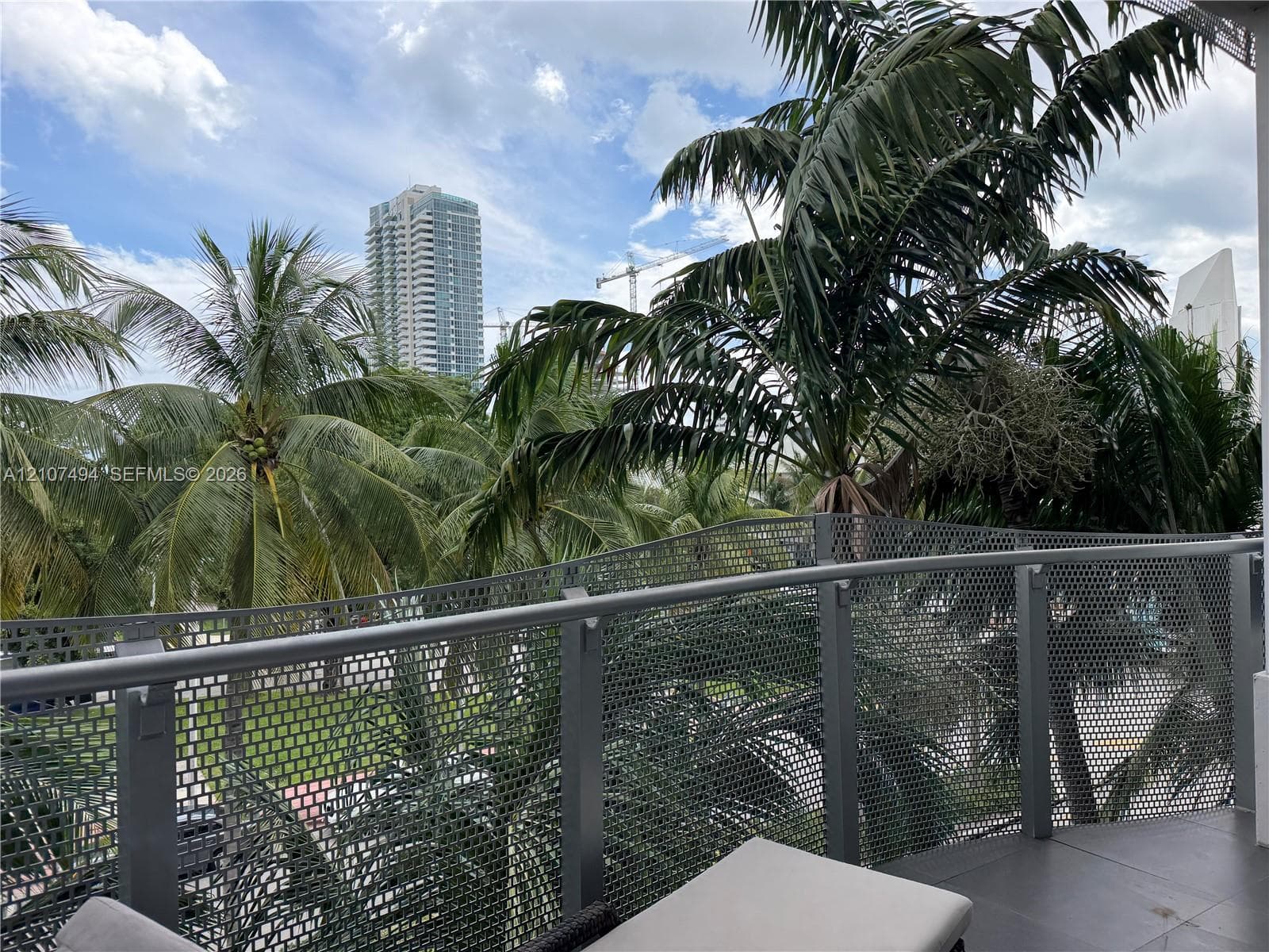 Private balcony featuring a grey metal mesh railing, horizontal handrail, and large-format tile flooring