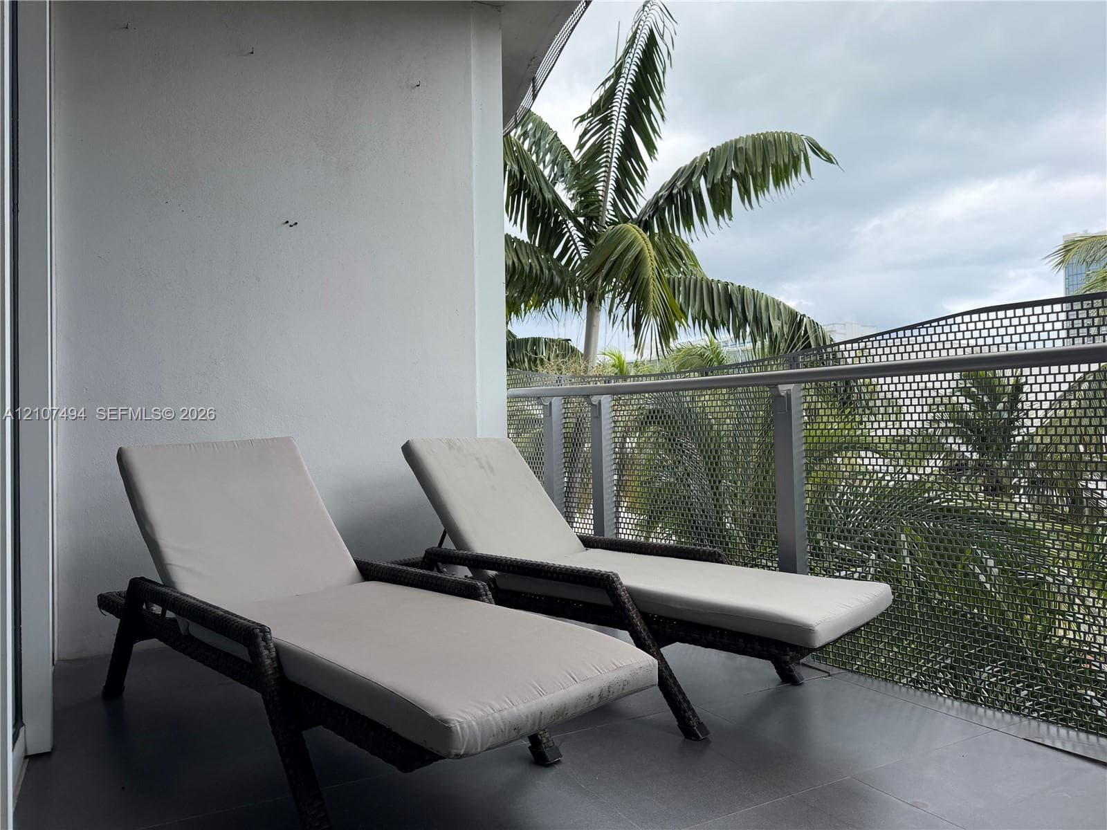 Covered balcony featuring grey floor tiling and a metal perforated railing