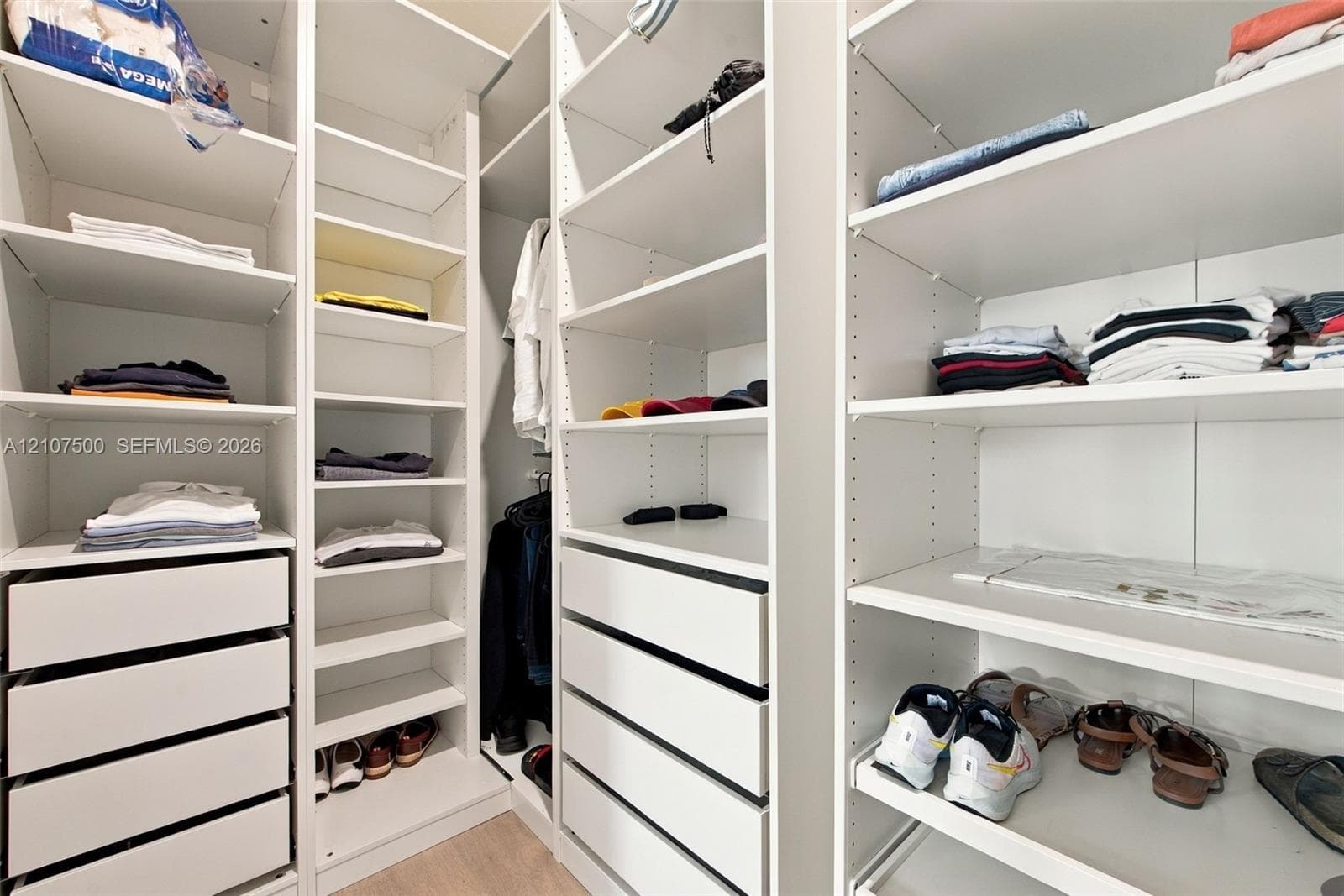 Custom closet system featuring white built-in shelving, adjustable storage racks, integrated cabinetry, and multi-tier drawer units