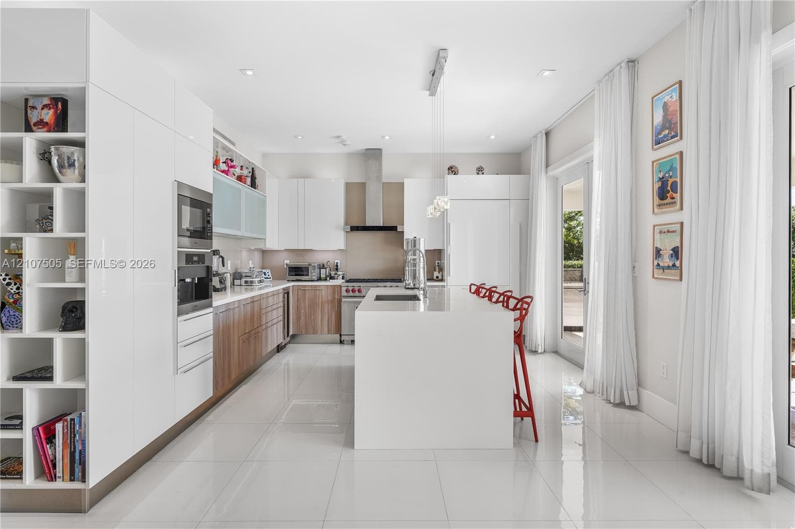 Kitchen featuring custom flat-panel cabinetry, a central island with a solid-surface countertop, built-in stainless steel appliances, a stainless steel range hood, and large-format porcelain tile flooring
