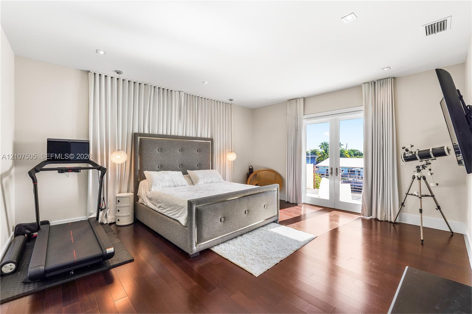 Spacious room featuring dark-toned wood-finish flooring, recessed lighting, and full-height wall drapery