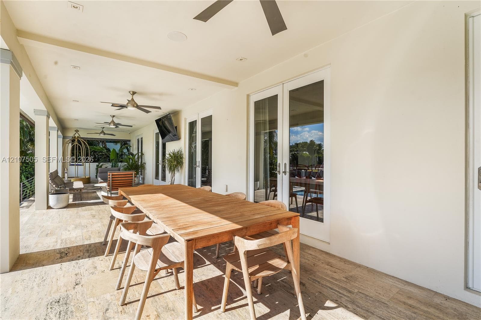 Covered outdoor patio featuring stone-finish flooring, ceiling-mounted fans, recessed lighting, and glass-paneled double doors