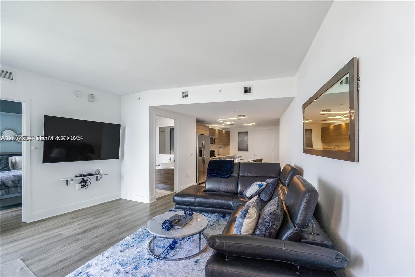 Open-concept interior featuring wood-finish flooring, recessed lighting, and wall-mounted mirror