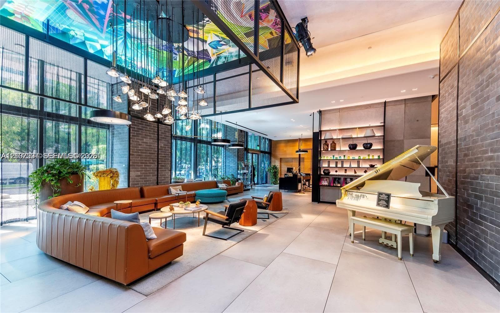 Floor-to-ceiling glass walls, large-scale contemporary light installation, textured brick feature walls, large-format tile flooring, and custom built-in shelving