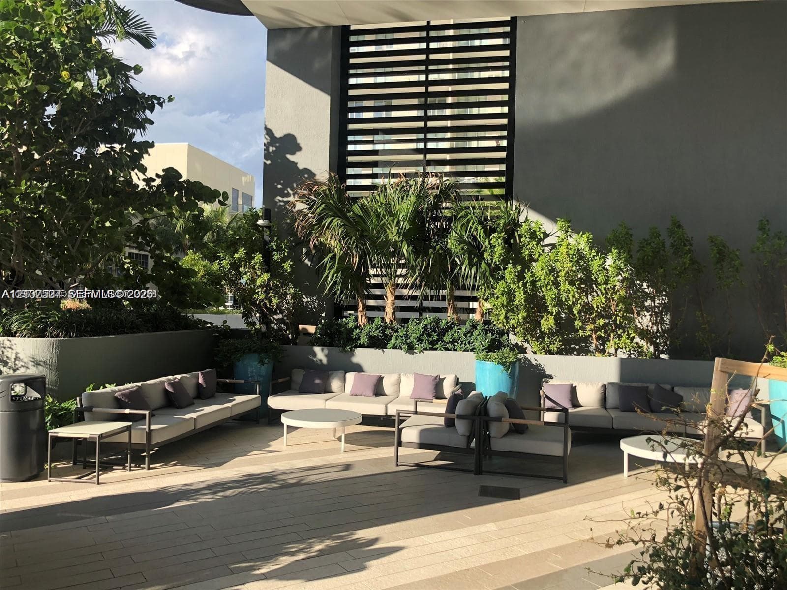 Outdoor terrace featuring large-format tile flooring, built-in concrete planters, and decorative metal privacy screening