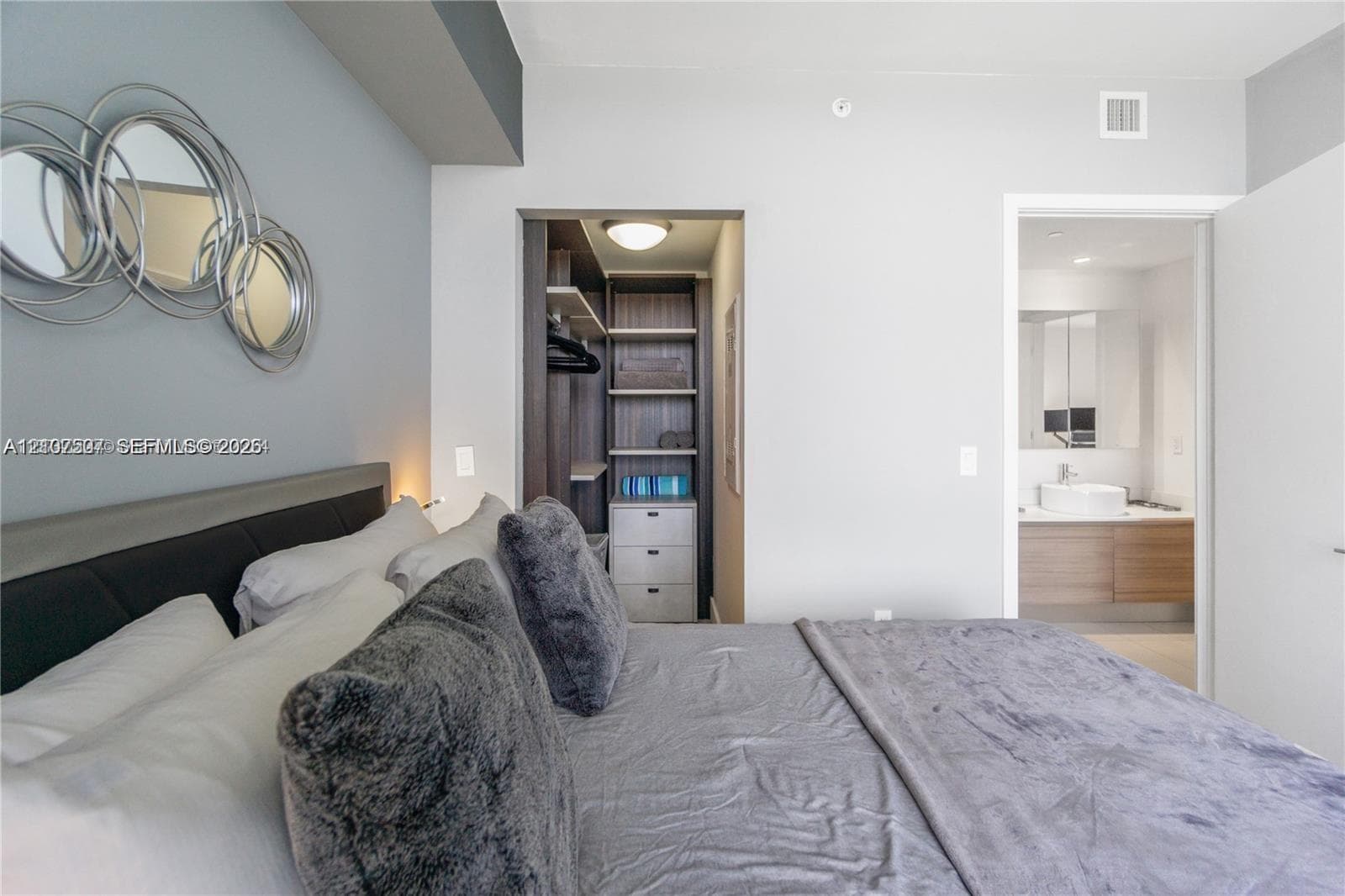 Custom walk-in closet with built-in shelving and drawers, wall-mounted floating wood-finish vanity, and integrated vessel sink