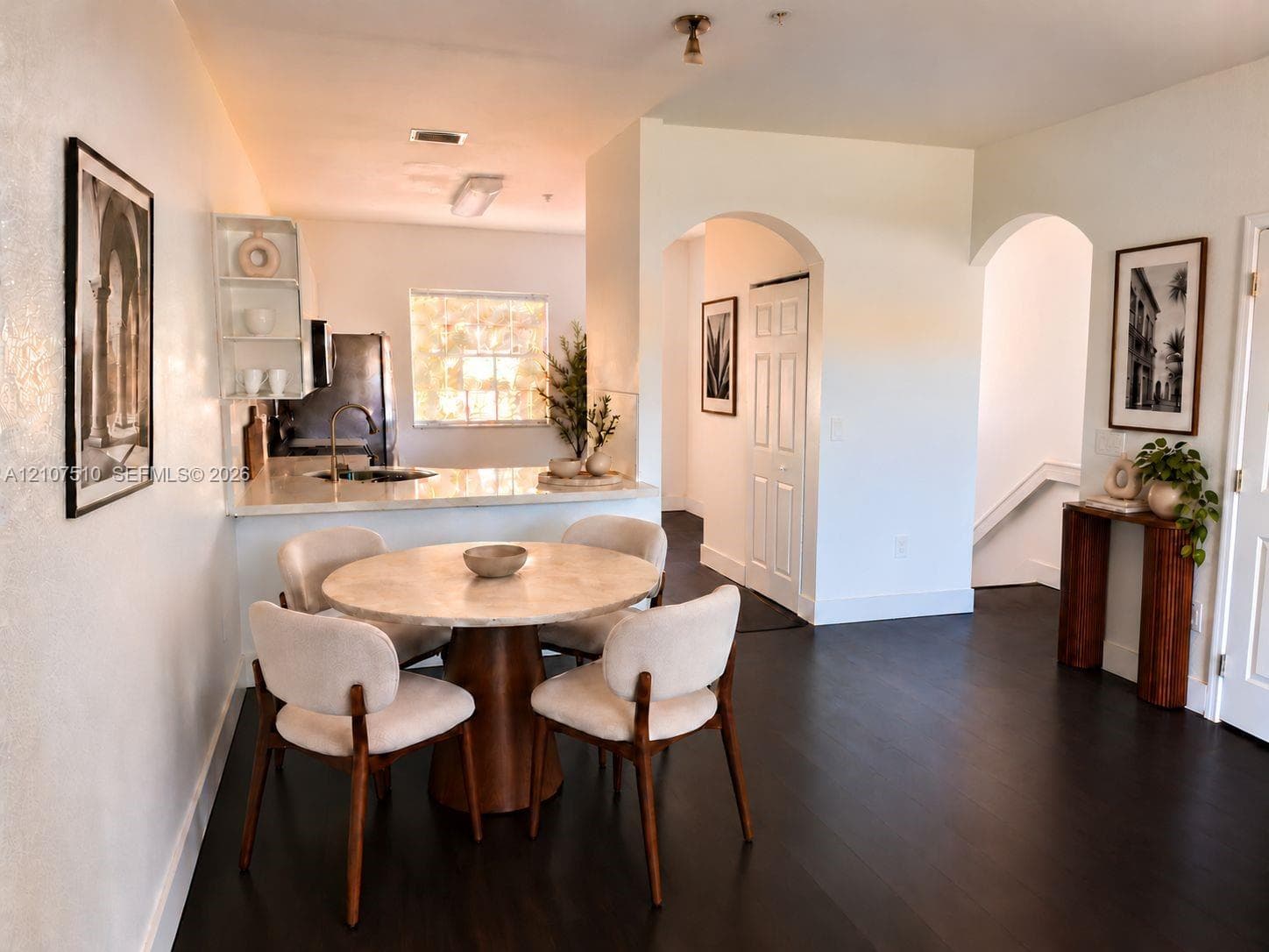 Kitchen featuring a breakfast bar with stone-surfaced countertops, dark wood-finish flooring, and arched architectural entryways