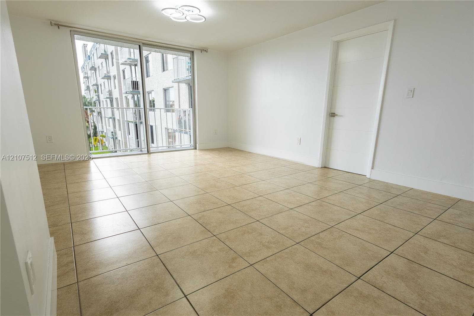 Large-format tile flooring, sliding glass door, metal-railed balcony, and flush-mount modern ceiling lighting